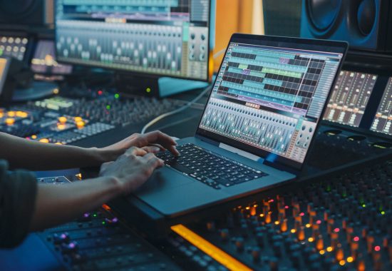 Modern Music Record Studio Control Desk with Laptop Screen Showing User Interface of Digital Audio Workstation Software. Equalizer, Mixer and Professional Equipment. Faders, Sliders. Record. Close-up